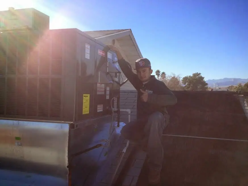 HVAC technician performing AC Tune-Up on a rooftop unit in Cave Springs