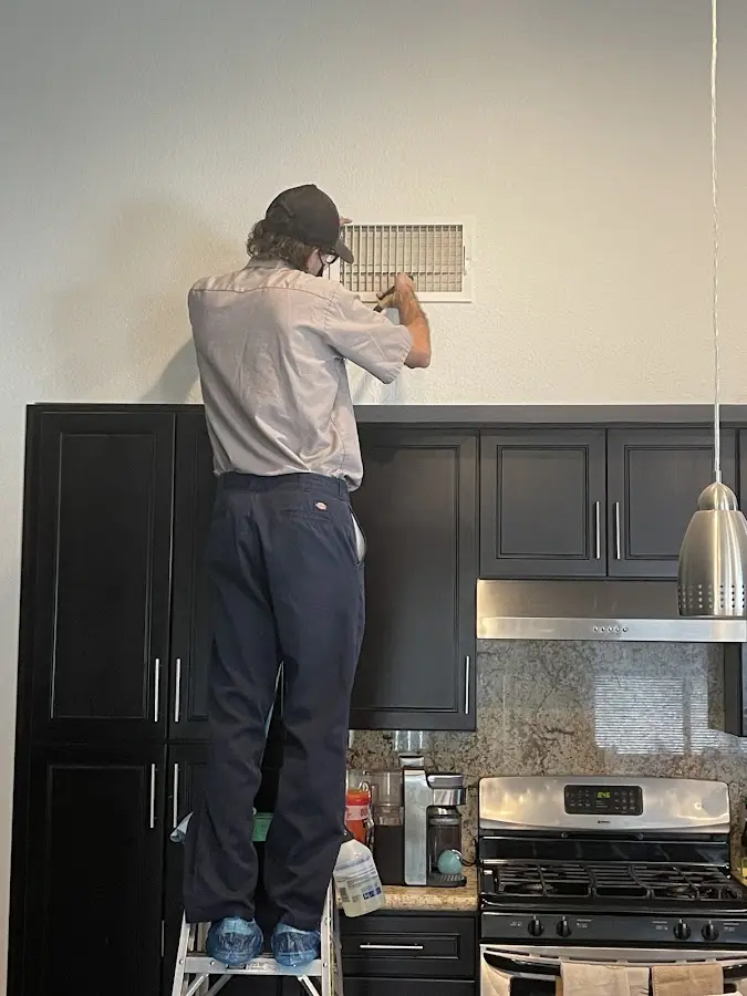 Technician inspecting an air vent during HVAC service in Cave Springs